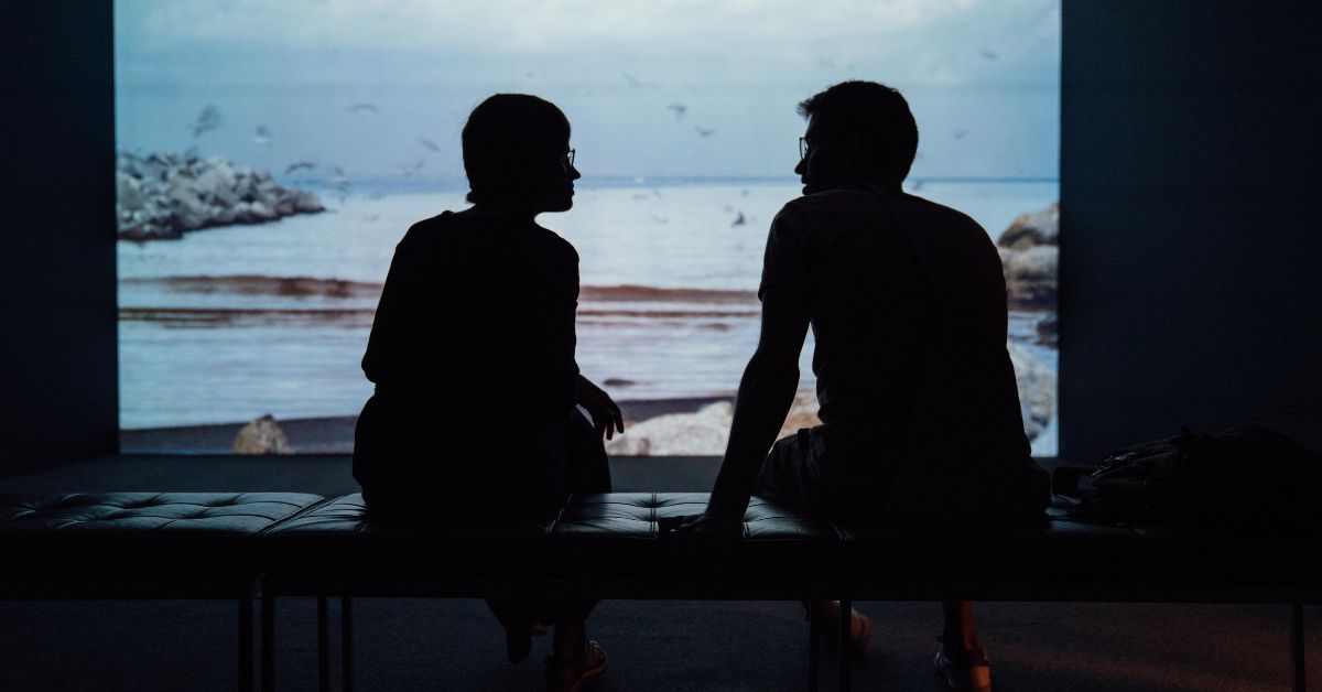 Two friends talking in front of a seaside landscape