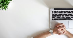 Man with hands folded at laptop