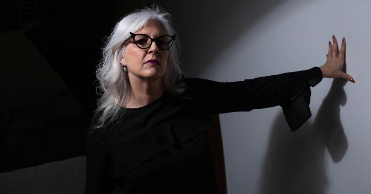 Mature woman standing with arm stretched out on a wall